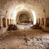 Un alto portale ci conduce al suo interno: un lungo stanzone con decine di aperture destinate a mucche e cavalli